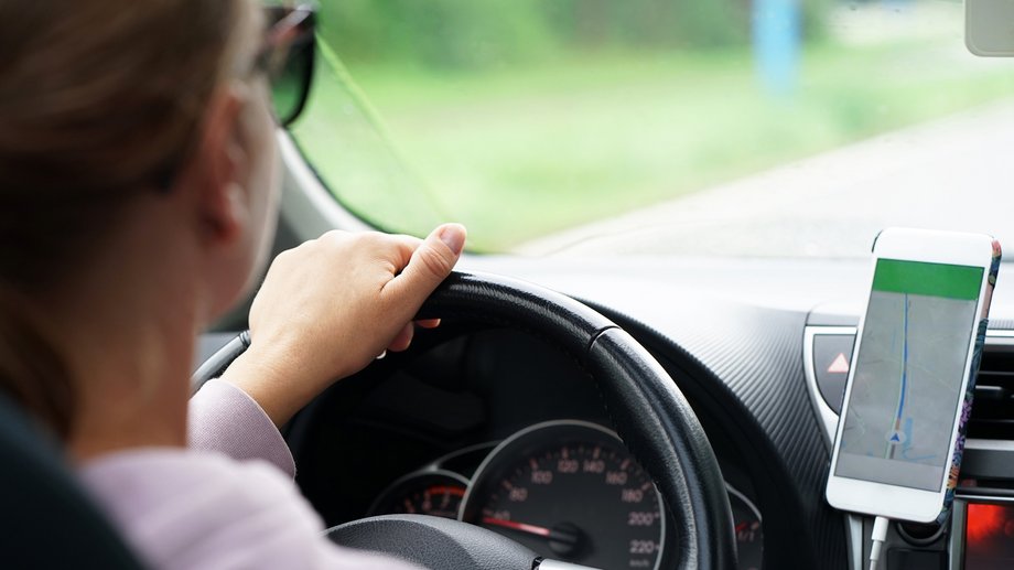 Autofahrerin fährt mit Navigationsgerät auf Straße