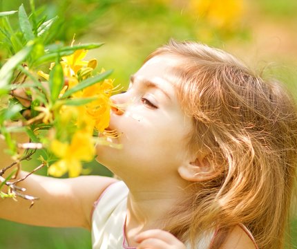 Kleines Mädchen riecht an einer gelben Blume